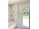 Bright bathroom featuring tiled shower, white tub, and glass door to the backyard at 1507 W Le Compte Dr, Tampa, FL 33604
