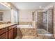Bathroom showcasing a vanity, soaking tub, and glass shower enclosure with neutral tile surround at 1634 Acadia Harbor Pl, Brandon, FL 33511
