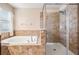 Bathroom showcasing a walk-in shower, soaking tub, and travertine tile surround at 1634 Acadia Harbor Pl, Brandon, FL 33511