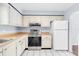 Cozy kitchen with white cabinets, stainless steel stove, and bright refrigerator at 1706 Belleair Forest Dr # 146, Belleair, FL 33756