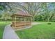 A wooden gazebo with bench seating provides a lovely focal point in the expansive, well-manicured yard at 18110 30Th St, Lutz, FL 33559