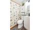 Well-lit bathroom featuring a toilet, vanity with modern fixtures, and a shower with a patterned curtain at 1912 E 97Th Ave, Tampa, FL 33612
