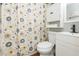 Well-lit bathroom featuring a toilet, vanity with modern fixtures, and a shower with a patterned curtain at 1912 E 97Th Ave, Tampa, FL 33612