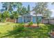 Quaint blue home featuring lush greenery and charming front yard landscaping at 1912 E 97Th Ave, Tampa, FL 33612