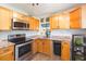 Well-lit kitchen featuring modern stainless steel appliances, granite countertops, and oak cabinets at 1912 E 97Th Ave, Tampa, FL 33612