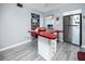 Spacious kitchen with red countertops, pantry shelving, stainless steel refrigerator, and gray tile flooring at 211 Pasadena N Ave # 109, St Petersburg, FL 33710