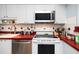 Well-lit kitchen featuring white cabinetry, stainless steel appliances and red countertops at 211 Pasadena N Ave # 109, St Petersburg, FL 33710