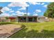 Expansive backyard with lush lawn, screened-in patio, and fence; kayaks hang on the home's exterior at 2325 W Knollwood Pl, Tampa, FL 33604