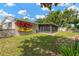 Lush backyard featuring a screened patio, storage shed, and vibrant green grass at 2325 W Knollwood Pl, Tampa, FL 33604