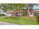 Charming pink home with a well-manicured front lawn and mature tree offering shade, with an attached garage and mailbox at 267 Snell Isle Ne Blvd, St Petersburg, FL 33704