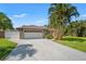 Home exterior featuring a driveway leading to the garage, with lush landscaping on a sunny day at 2708 W Bird St, Tampa, FL 33614