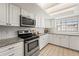 Well lit kitchen featuring stainless steel appliances, light granite countertops and white cabinetry at 2708 W Bird St, Tampa, FL 33614