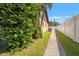 A shady side yard is shown with a walkway, partial fence, and manicured landscaping at 2708 W Bird St, Tampa, FL 33614