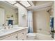 Bright bathroom featuring tiled shower/tub and white vanity with marble countertop and skylight at 2868 Denmarsh Ct, Palm Harbor, FL 34684