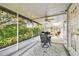 Charming screened patio features a dining table, ceiling fan, grill, and access to both the backyard and interior at 2868 Denmarsh Ct, Palm Harbor, FL 34684