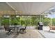 Relaxing screened patio with ceiling fan, dining set, grill, and view of the backyard at 2868 Denmarsh Ct, Palm Harbor, FL 34684