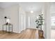 Inviting foyer featuring wood-look flooring, a stylish light fixture, and a view of the front door at 30260 Birdhouse Dr, Wesley Chapel, FL 33545