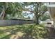 An expansive backyard with a mature tree is surrounded by fencing with a storage shed and patio at 3226 Coventry N, Safety Harbor, FL 34695