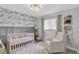 A charming Bedroom with mountain-themed wallpaper, stylish light fixture, crib, chair and decor at 3226 Coventry N, Safety Harbor, FL 34695