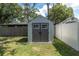 A storage shed with double doors provides backyard storage and is framed by fences and mature trees at 3226 Coventry N, Safety Harbor, FL 34695