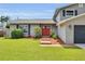 Inviting home entrance with a red front door, complemented by the home's well-kept lawn and landscaping at 3721 Casaba Loop, Valrico, FL 33596