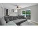 Bright living room with gray sofa, ceiling fan, and sliding glass doors to the pool at 3721 Casaba Loop, Valrico, FL 33596
