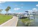 View of boat dock featuring multiple boats on boat lifts, manicured lawn, and waterfront access at 400 64Th Ave # 202, St Pete Beach, FL 33706