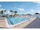 View of a shared swimming pool with lounge chairs and the water in the background on a sunny day with scattered clouds at 400 64Th Ave # 202, St Pete Beach, FL 33706