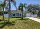 Charming single-story home with arched windows, yellow door, attached garage, and well-maintained lawn and palm trees at 4707 Barrett Ct, Tampa, FL 33617
