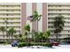 Exterior view of the Continental Condominium with lush landscaping, palm trees, and the American flag on display at 4775 Cove Cir # 803, St Petersburg, FL 33708