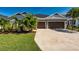 Charming home featuring a two-car garage, well-manicured lawn, and tropical landscaping at 4906 Los Robles Ct, Palmetto, FL 34221