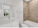 Bright bathroom featuring a white vanity with marble countertop, tub, and stylish beige tiled shower at 50 64Th S St, St Petersburg, FL 33707