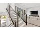 Bright, modern staircase with sleek, dark metal railing and a view to the living room area at 50 64Th S St, St Petersburg, FL 33707