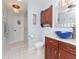 This bathroom features a bowl sink, wooden cabinets, updated lighting, and white tiled floors at 6207 Ridge Top Dr, New Port Richey, FL 34655