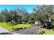 Landscaped home featuring mature trees, lush lawn, and a paved driveway leading to a two-car garage at 6207 Ridge Top Dr, New Port Richey, FL 34655