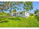 Charming single-story home features a lush green lawn, mature oak tree, and inviting front porch at 6219 Hampton N Dr, St Petersburg, FL 33710