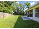 Well-manicured backyard featuring lush lawn, mature trees, and a covered patio at 6318 Ashfield Pl, Wesley Chapel, FL 33545