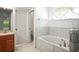 Bathroom with tiled tub, glass shower, and charming arched window over the tub at 6318 Ashfield Pl, Wesley Chapel, FL 33545
