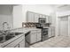Well-lit kitchen with stainless steel appliances, modern cabinetry, tile backsplash and flooring at 6318 Ashfield Pl, Wesley Chapel, FL 33545
