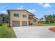 Beautiful tan two-story home with a two-car garage, balcony, and lush landscaping at 6780 Greenbrier Dr, Seminole, FL 33777
