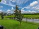 A serene backyard view features a tranquil pond, manicured lawn, and secure black fencing for added privacy at 8119 Trimbelle Ter, Parrish, FL 34219
