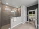 A tiled walk-in shower with glass enclosure featuring a window and stainless steel shower head and view of the bedroom at 8119 Trimbelle Ter, Parrish, FL 34219