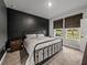 Well-lit bedroom with a dark accent wall, comfortable bed, and view of the outdoors through the windows at 8119 Trimbelle Ter, Parrish, FL 34219