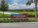 Landscaped Riverfield sign near the community with a pond and well-maintained lawns at 8119 Trimbelle Ter, Parrish, FL 34219