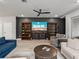 Bright living room with bookshelves, television, and a comfortable sectional sofa arranged around a coffee table at 8119 Trimbelle Ter, Parrish, FL 34219