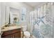 Well-lit bathroom with a decorative shower curtain, granite countertop, and a large mirror at 8305 Praise Dr, Tampa, FL 33625