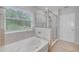 Bright bathroom with a separate tub and shower, featuring neutral tiling and a large window for natural light at 8305 Praise Dr, Tampa, FL 33625
