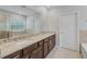 Bathroom features a double vanity with granite countertops, dark wood cabinets and large mirror at 8305 Praise Dr, Tampa, FL 33625