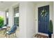 Cozy front porch with seating and a welcoming wreath on the blue front door and a checkered welcome mat at 8305 Praise Dr, Tampa, FL 33625