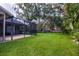 The backyard shows a screened lanai, mature trees, and lush lawn extending from the house at 8901 Eagle Watch Dr, Riverview, FL 33578